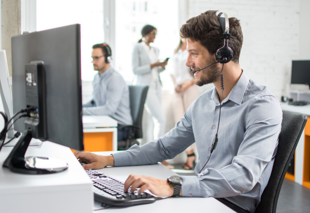 Visual of man at computer wearing a headset providing back office customer support